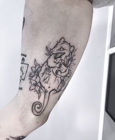 a tattoo on the leg of a person with a lizard and flowers around her arm