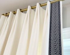 a close up of a white curtain with a black and white tie hanging from it's side