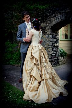 a man in a suit and tie hugging a woman wearing a dress with ruffles