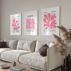 a living room with white couches and pink art on the wall above them in front of a window