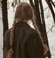 a woman standing in the snow with her back turned to the camera and braided hair