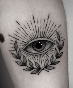 an all seeing eye tattoo on the left thigh, with leaves and sunburst around it