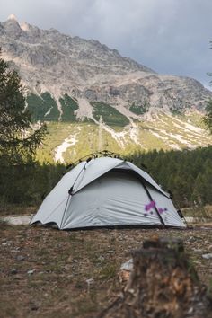 a tent pitched up on the ground with mountains in the background