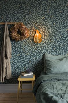 a bedroom with blue wallpaper and a wreath on the wall next to a bed