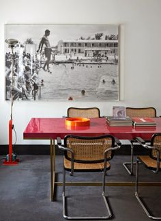 a dining room table with chairs and a painting on the wall above it that has people swimming in a pool