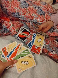 someone is playing cards on the bed with their hand holding them up to show it