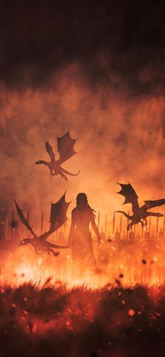 a woman standing in the middle of a field surrounded by dragon silhouettes on fire