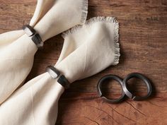 two pairs of scissors sitting on top of a wooden table next to a white scarf