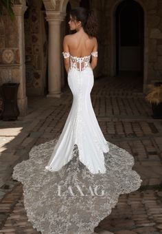 a woman in a white wedding dress standing on a brick walkway with her back to the camera