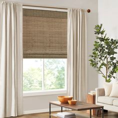 a living room with a couch, coffee table and window covered in bamboo roman shades