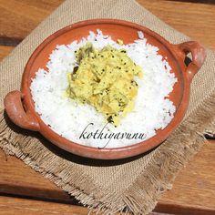 a bowl filled with rice and meat on top of a wooden table next to a napkin