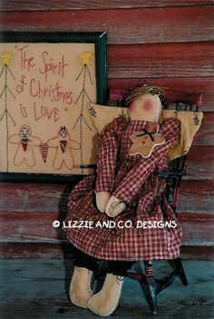 a doll is sitting on a chair next to a sign that says the spirit of christmas is love