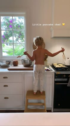 a small child standing on a stool in the kitchen