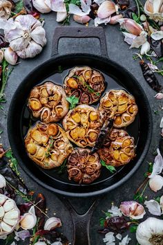 an overhead view of some food in a pan with garlic and herbs on the side