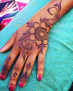 a woman's hand with hennap and flowers on her left hand,