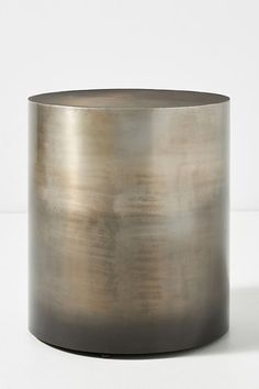 a round metal vase sitting on top of a white table