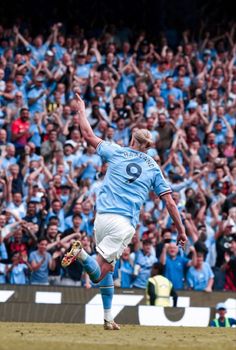 a man kicking a soccer ball on top of a field in front of a crowd