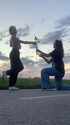 two women are sitting on the ground and one is holding a flower in her hand