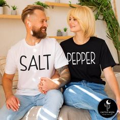 Custom made to order SALT or PEPPER unisex short sleeve couples t-shirt.  (Each shirt is purchased separately.) Photo shows Matte Black Design on Salt Shirt and Matte White Design on the Pepper Shirt. ADULT:  These soft and comfy shirts are high quality unisex shirts.  The unisex adult shirts are a slim semi-fitted cut.  So they are more slim and fitted for a man.  If you want a looser fit I suggest a size up.  They would run pretty true to a loose fit in womens sizing.  I have included the sizing charts by the manufacturers above in the photos.  Please take your favorite comfy shirt, lay it on a flat surface and compare the measurements of your favorite fitting shirt to the manufacturer's specs. KIDS:  These soft and comfy bodysuits and tees run pretty true to size to a little on the smal Couples Cotton T-shirt Gift, Couples Cotton T-shirt For Gift, Couples Cotton Tops With Letter Print, Funny Short Sleeve Tops With Custom Text, White Short Sleeve Couples T-shirt, White Matching Couples T-shirt, Couples White Short Sleeve T-shirt, Black Cotton Couples T-shirt, Black Cotton T-shirt For Couples