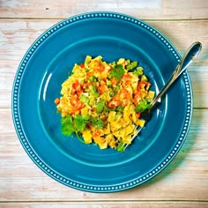 a blue plate topped with pasta and veggies on top of a wooden table