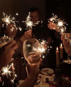 people holding wine glasses with sparklers in them