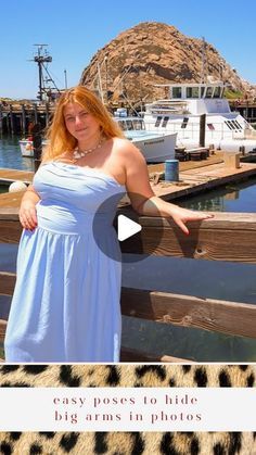 a woman in a blue dress is standing on a dock with her arms spread out