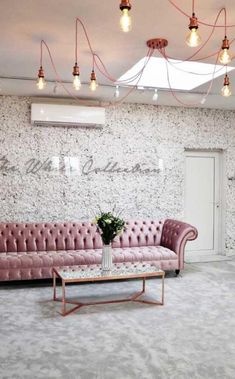 a living room with pink couches and chandeliers hanging from the ceiling above