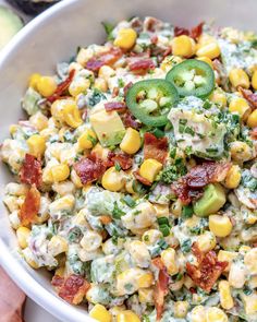 a white bowl filled with corn salad and topped with jalapeno wedges