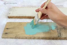 someone using a brush to paint some wood planks with blue and white paint on them