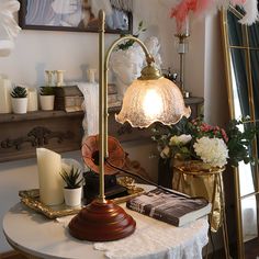 a white table topped with a lamp next to a vase filled with flowers and candles