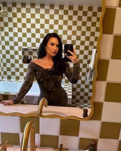 a woman taking a selfie in front of a bathroom mirror with a sink and faucet