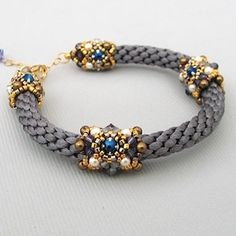 the bracelet is decorated with blue and gold beads on gray braided fabric, which has two charms attached to it