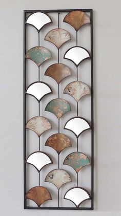 a decorative metal wall hanging on the side of a white wall with an iron frame