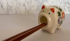 an elephant shaped toothbrush holder with chopsticks sticking out of it's mouth