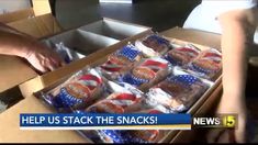 a box filled with snacks sitting on top of a table next to a person's hand