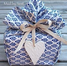 a blue and white gift bag with a heart on it's side, tied to a wooden table