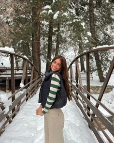 a woman standing on a bridge in the snow