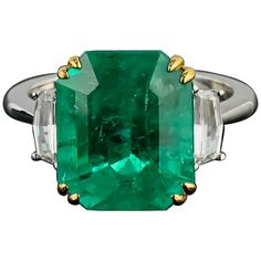 Magnificent Colombian Emerald: This ring features an exceptional 7.14-carat octagonal Colombian emerald, renowned for its vibrant, deep green color and unparalleled clarity, making it a highly prized gemstone. Flanked by two cadillac-cut diamonds totaling 0.48 carats, these diamonds add a sophisticated sparkle that complements the grandeur of the central emerald. The color of the diamonds is G , the clarity is VS1 . Set in 18K white gold with a total weight of 5.47 grams, the setting enhances th Emerald Statement Ring, Colombian Emerald Ring, Triangle Diamond, Platinum Diamond Rings, Emerald Diamond Ring, Colombian Emeralds, Green Jewelry, Diamond Cocktail Rings, Emerald Engagement