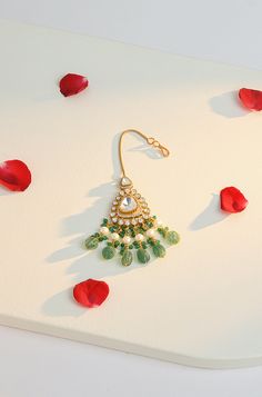 Elevate your style with this stunning maangtikka, expertly crafted with polki and cubic zirconia to create a traditional statement piece. The intricate design includes dangling green jade stones and pearls, adding a touch of elegance to any outfit. Perfect for enhancing your look with sophistication and charm, this maangtikka is a must-have accessory. Finish: 22KT Gold Plating Material: Silver, Copper Alloy, Polki, CZ Color: Green Size: One Size Closure Type: Hook Box Contains: 1 Maangtikka Green Kundan Chandbalis For Reception, Green Chandbalis For Diwali Reception, Green Bollywood Chandbalis For Reception, Green Chandbalis For Reception And Diwali, Green Kundan Tikka For Eid, Green Tikka For Eid Gift, Green Stone Work Tikka For Festivals, Bollywood Green Tikka With Stone Work, Bollywood Style Green Tikka With Stone Work