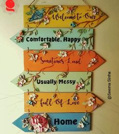 four colorful wooden signs hanging from the side of a wall with words on them that say welcome, happy, sometimes, usually messy, full of love