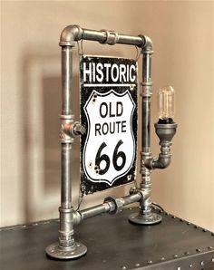 an old route 66 sign mounted to the side of a metal shelf next to a lamp