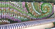 a bench sitting in front of a wall covered with lots of plants on it's side