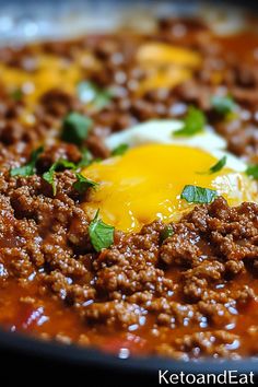 a close up of food in a pan with meat and an egg on the top