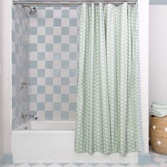 a bath tub sitting next to a shower curtain in a bathroom with checkered tile on the walls