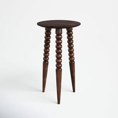 a small wooden table with three legs and a round top, on a white background