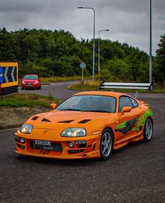 an orange sports car is parked on the street