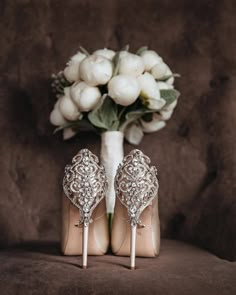 a pair of high heeled shoes sitting next to a bouquet of flowers