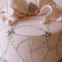 a white cake decorated with pearls and bows