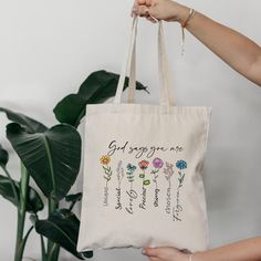 a person holding a tote bag with flowers on it