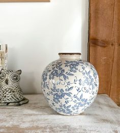 an owl figurine sitting next to a blue and white vase on a table